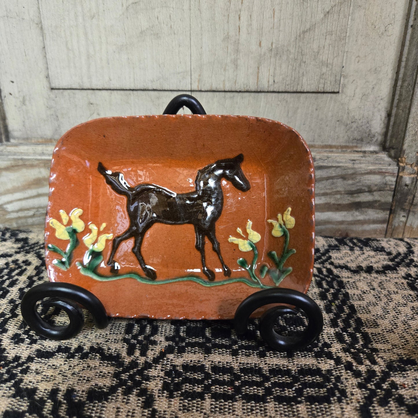 Small rectangular redware plate with horse and flower motive in a wrought iron plate stand