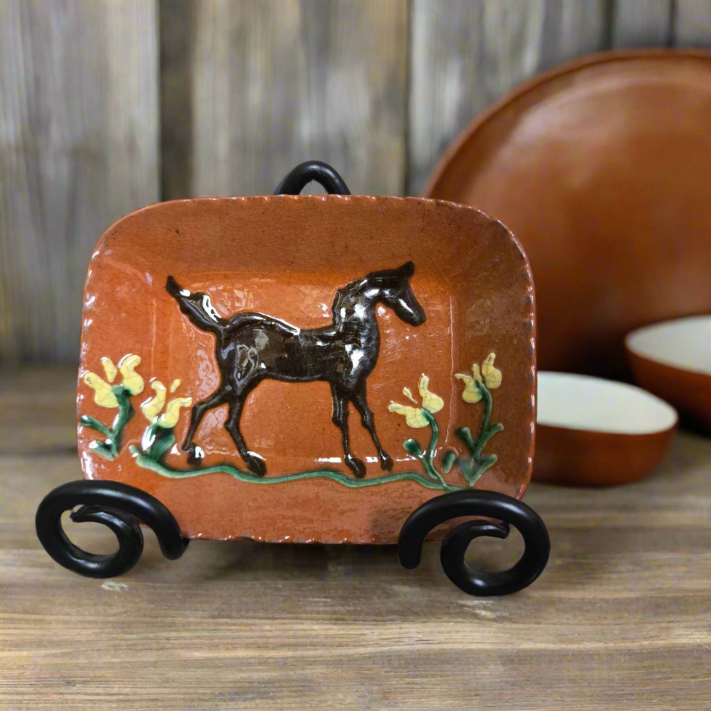 Small rectangular redware plate with horse and flower motive in a wrought iron plate stand