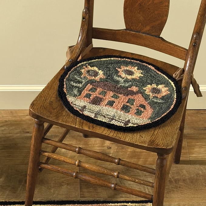 A hooked chair pad with a house and sunflower design, placed on a wooden chair.