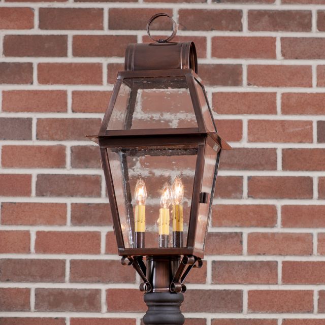 Decorative outdoor lamp with glass cover against a brick wall