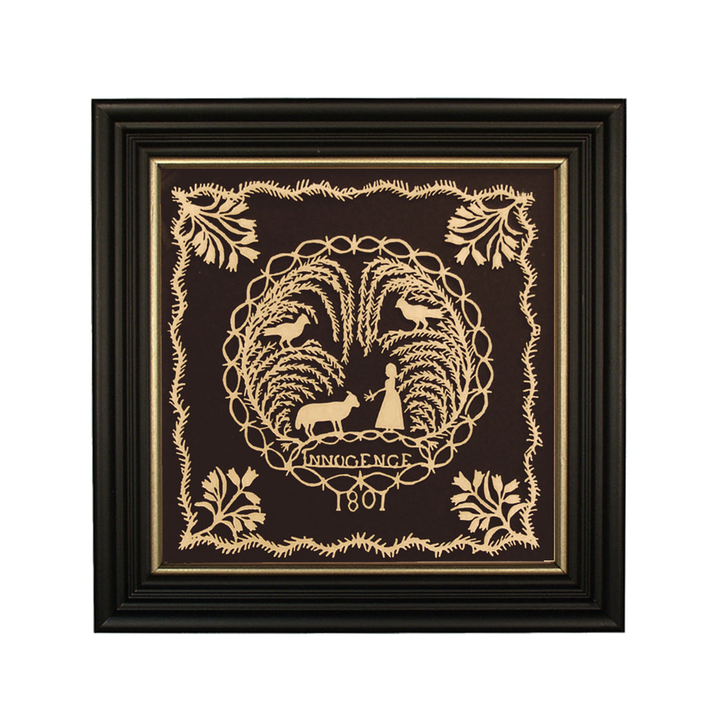 Framed scherenschnitte artwork featuring a historical or farmhouse design with birds, trees, and the year 1801 in the center, enclosed in a black wood frame with gold trim.