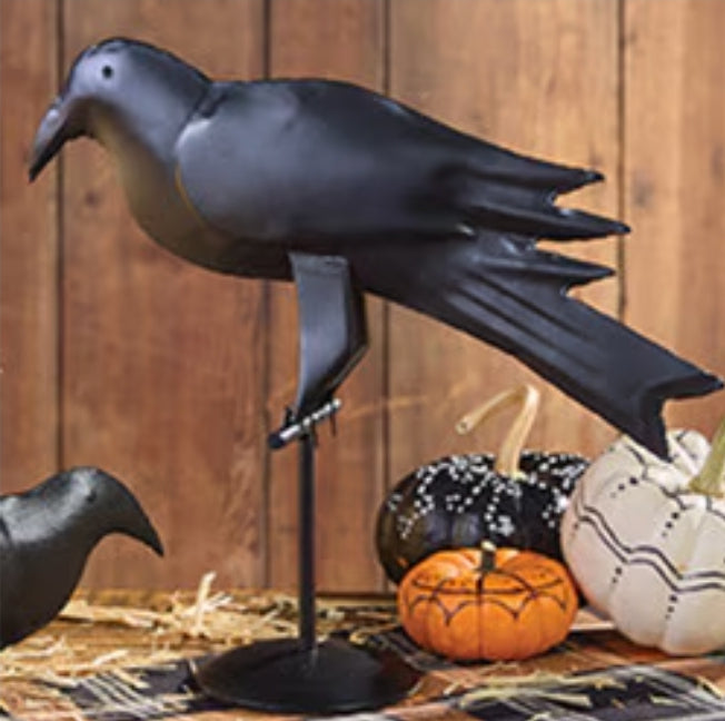 Black iron crow with pumpkins on wood surface