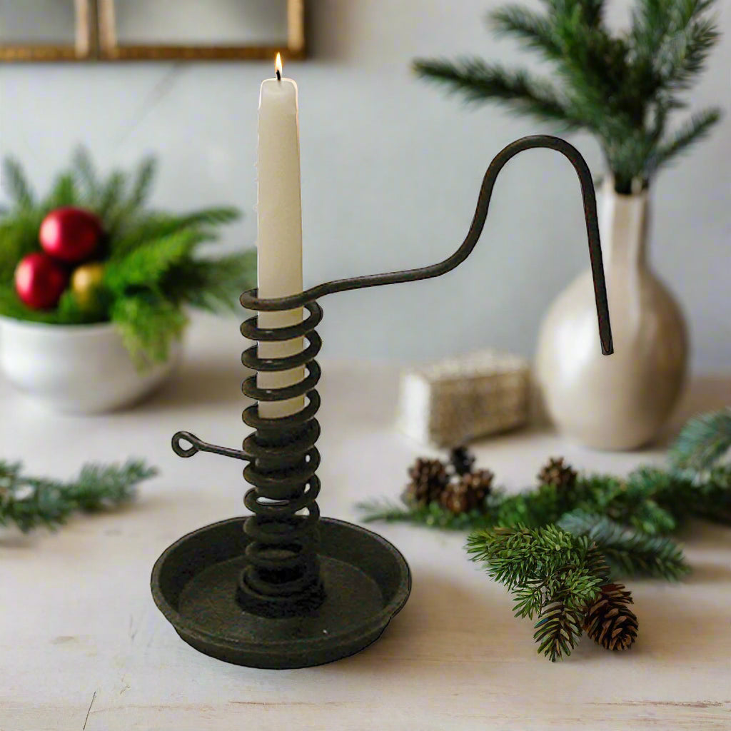 An iron spiral courting candle holder with a black finish, featuring a handle and a wide base designed to hold a candle.