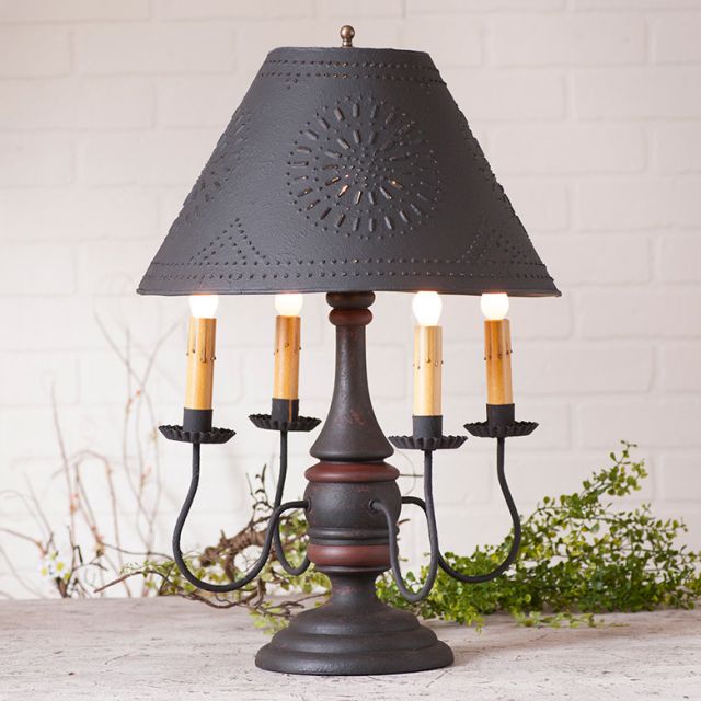 Decorative table lamp with a black shade and candle-like fixtures on a light background
