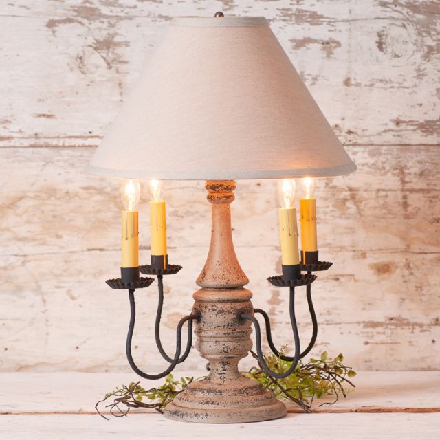Decorative table lamp with a rustic base and beige lampshade against a wooden background
