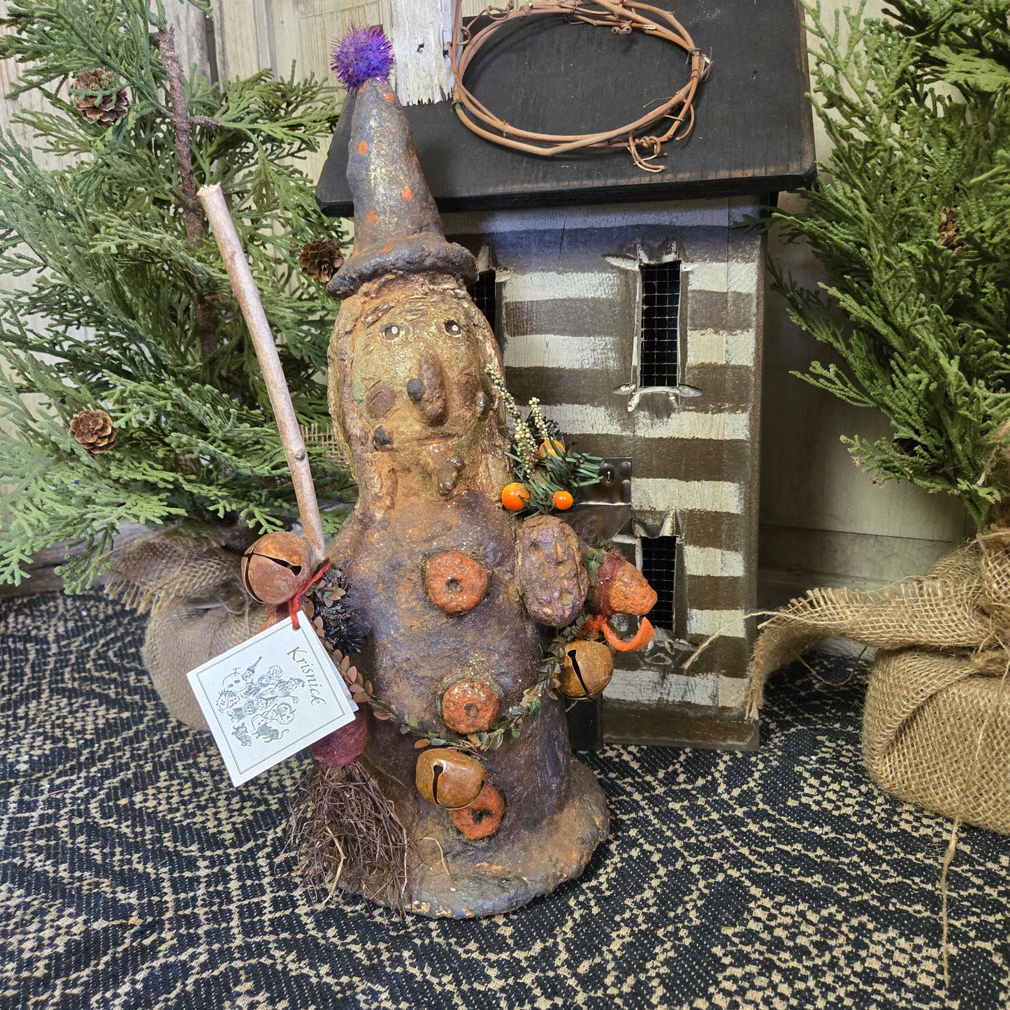 A handcrafted chalkware decoration depicting a whimsical witch with pumpkins and a broom, intended for Halloween decoration.