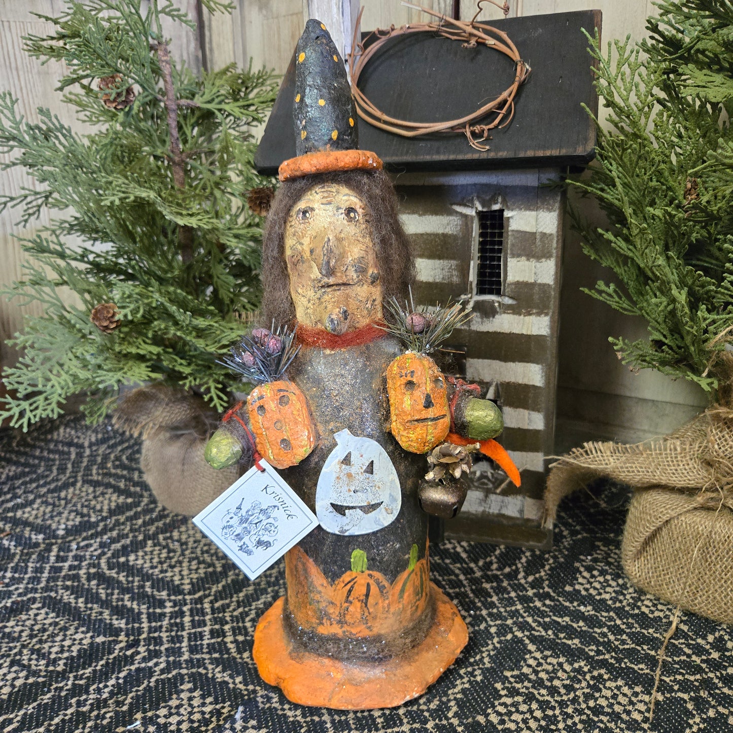 A handcrafted figurine of a witch with pumpkins, intended as Halloween decor.