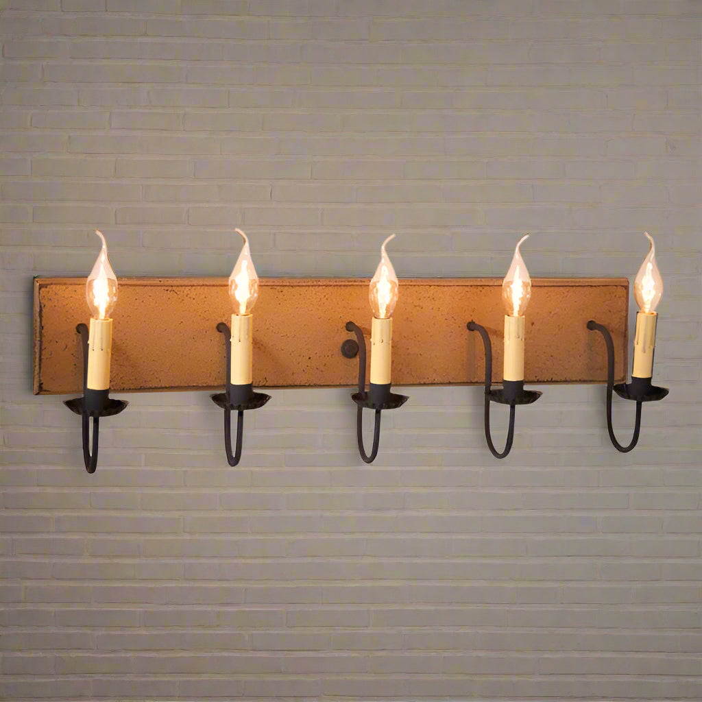 A pearwood finish vanity light with textured black arms and crimped pans, featuring five lit candelabra-style bulbs.