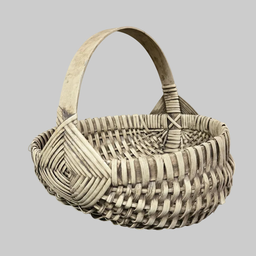Woven basket with geometric pattern on a rustic wooden surface with greenery