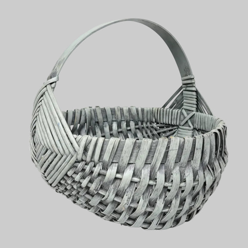 Primitive woven egg basket on a wooden surface with greenery