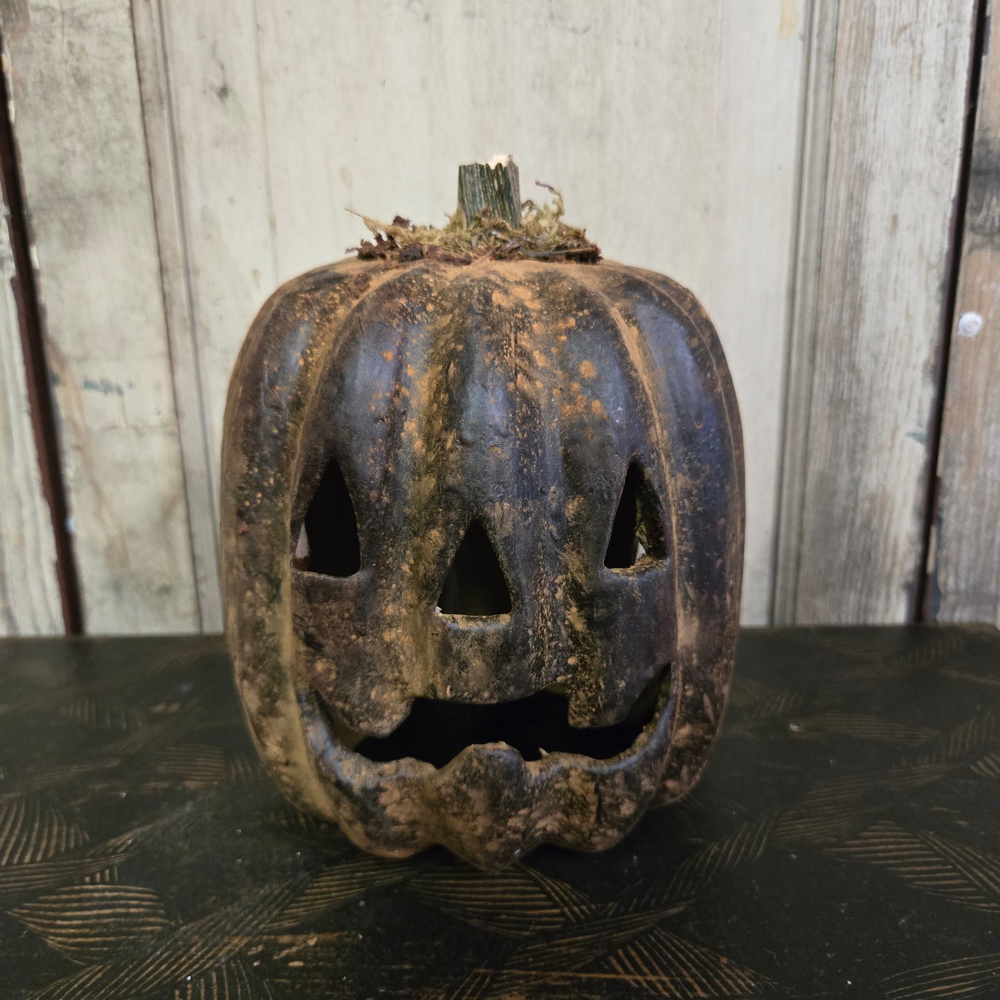 Worn-out pumpkin with a carved face on a wooden surface
