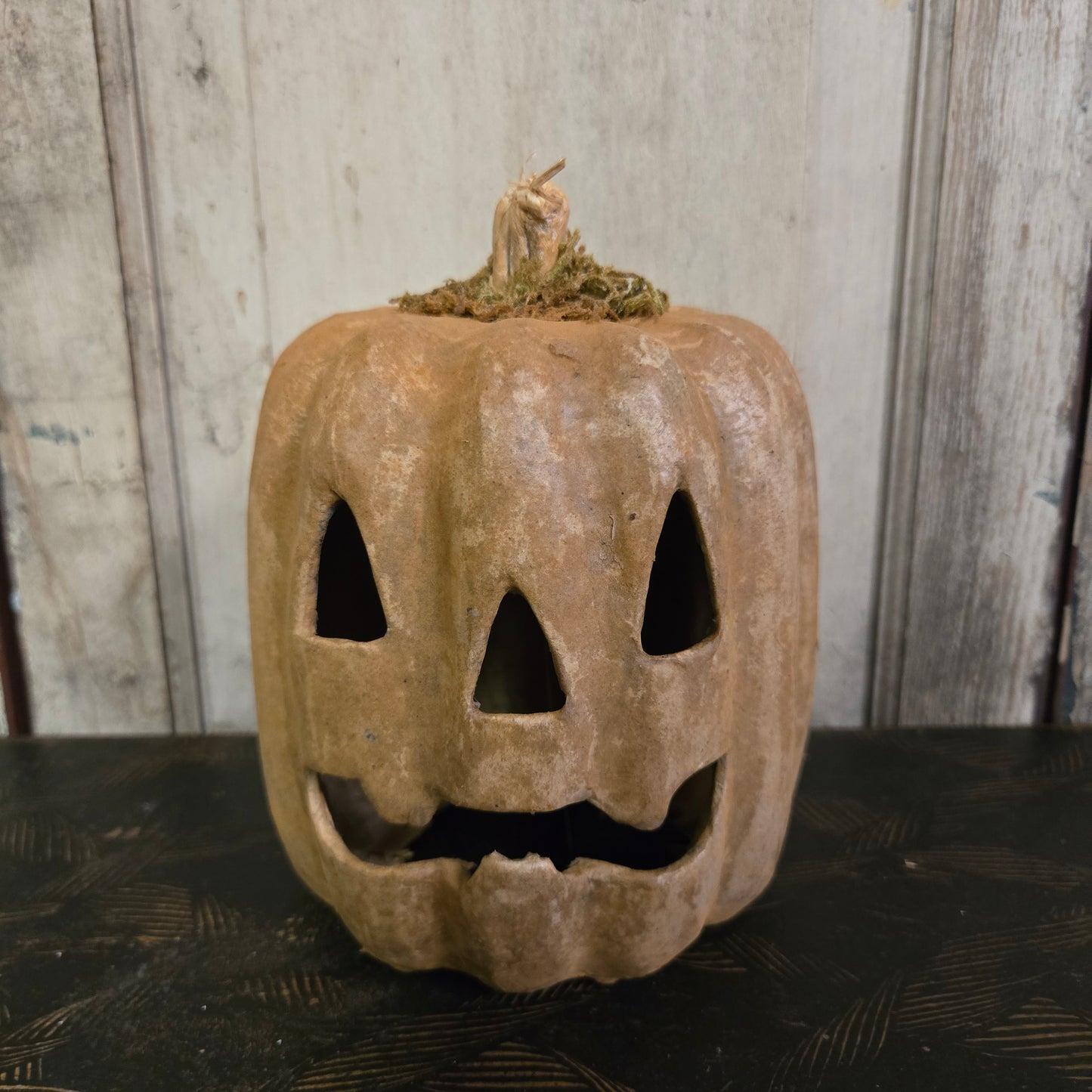 Vintage-style pumpkin with cut-out face on a wooden surface