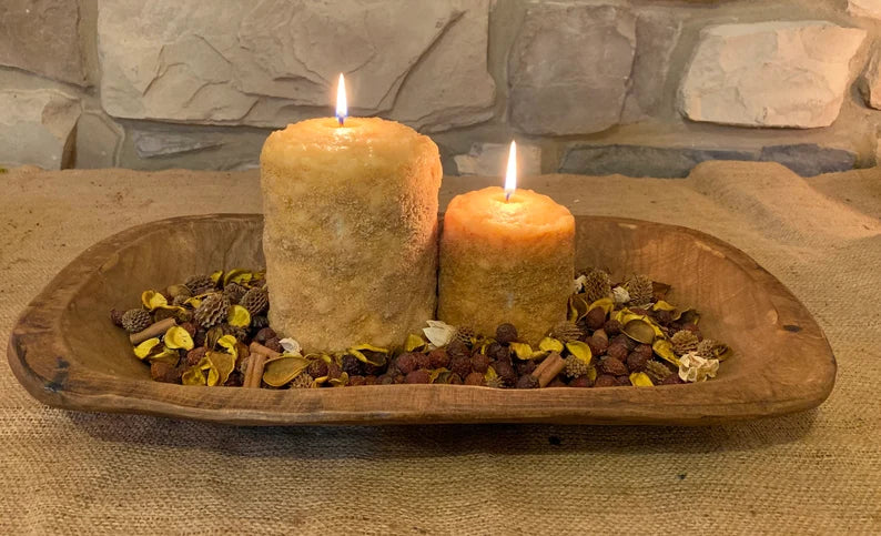 Two large hearth candles with a lemon fragrance, placed on a wooden hearth, surrounded by decorative ingredients.