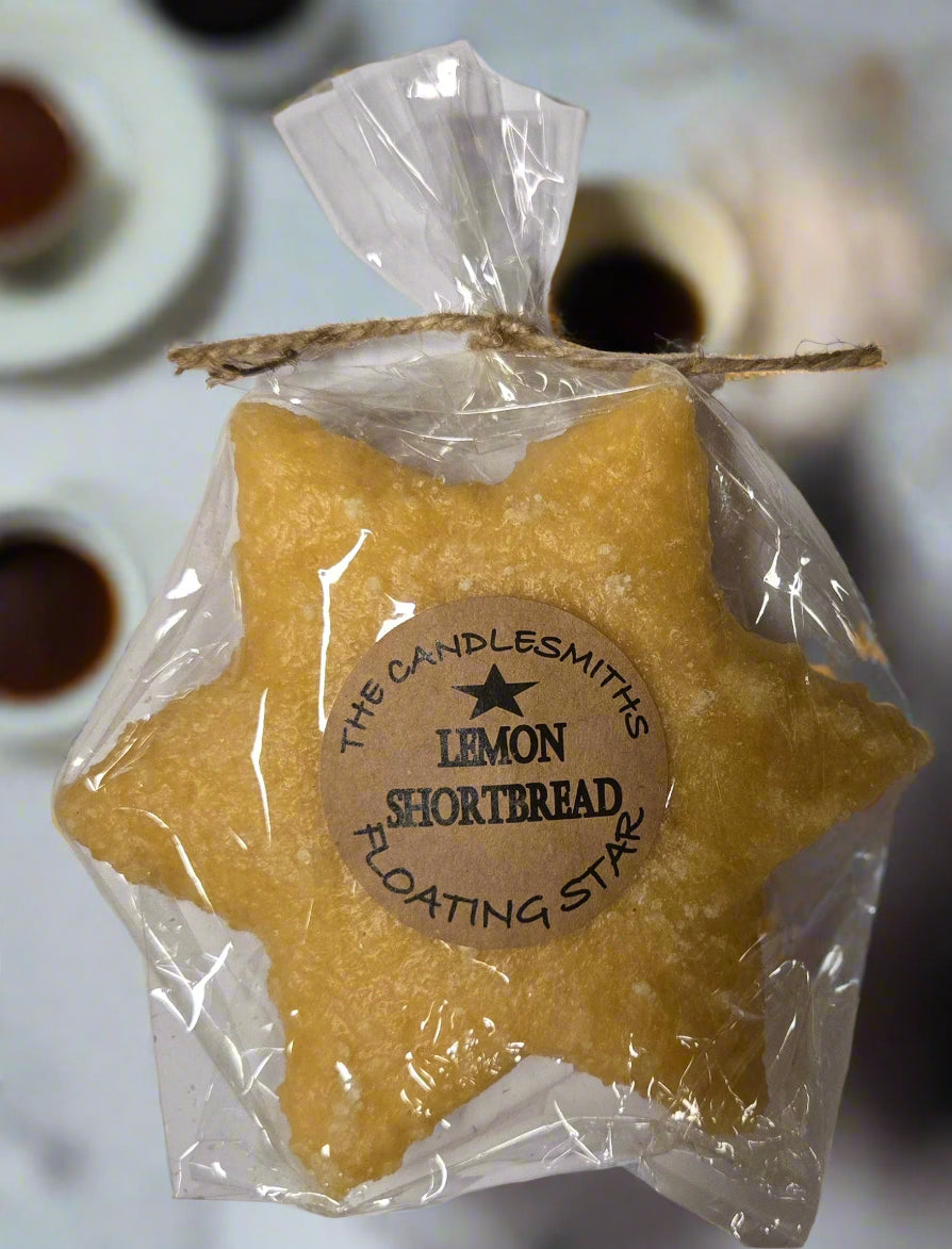 A packaged floating candle shaped like a large star with lemon shortbread, yellow in color, branded by The CandleSmith.