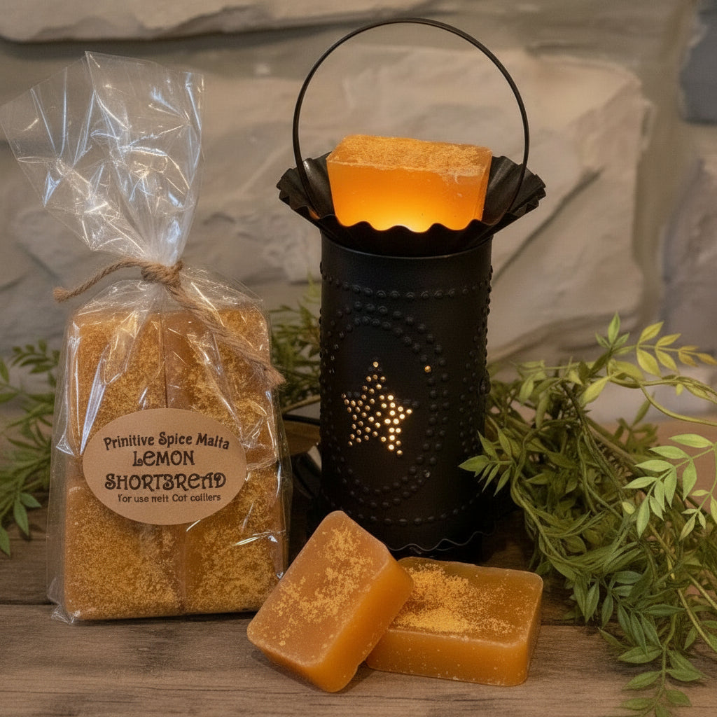 A set of lemon shortbread wax melts displayed in a black holder with a clear package overhead and greenery in the background.