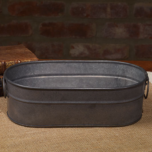 Oval tin pan with ringed handles in front of a brick ball