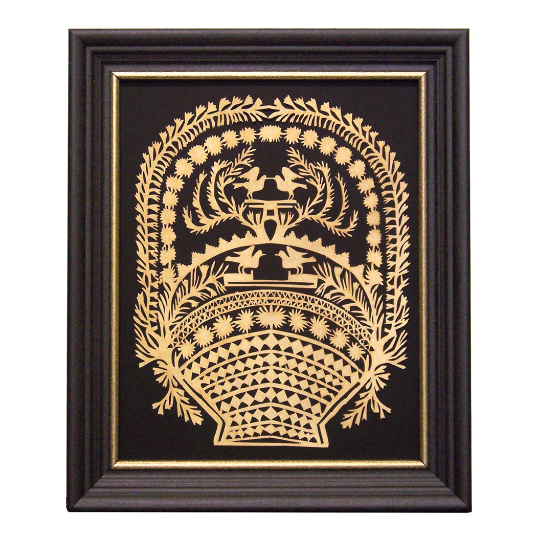 A framed paper cutting art of a basket with birds, designed with intricate scherenschnitte patterns, displayed in a black frame with gold trim.