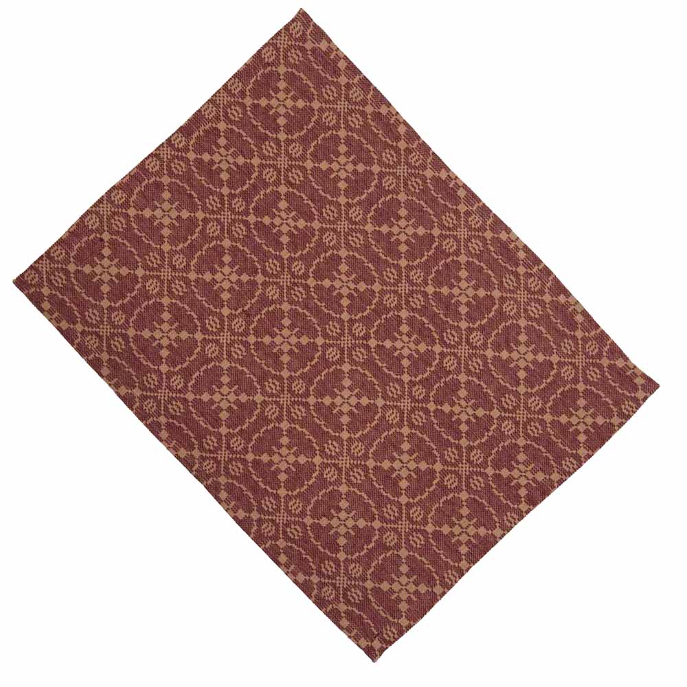 A rectangular barn red jacquard placemat with an intricate woven geometric design, laying flat.