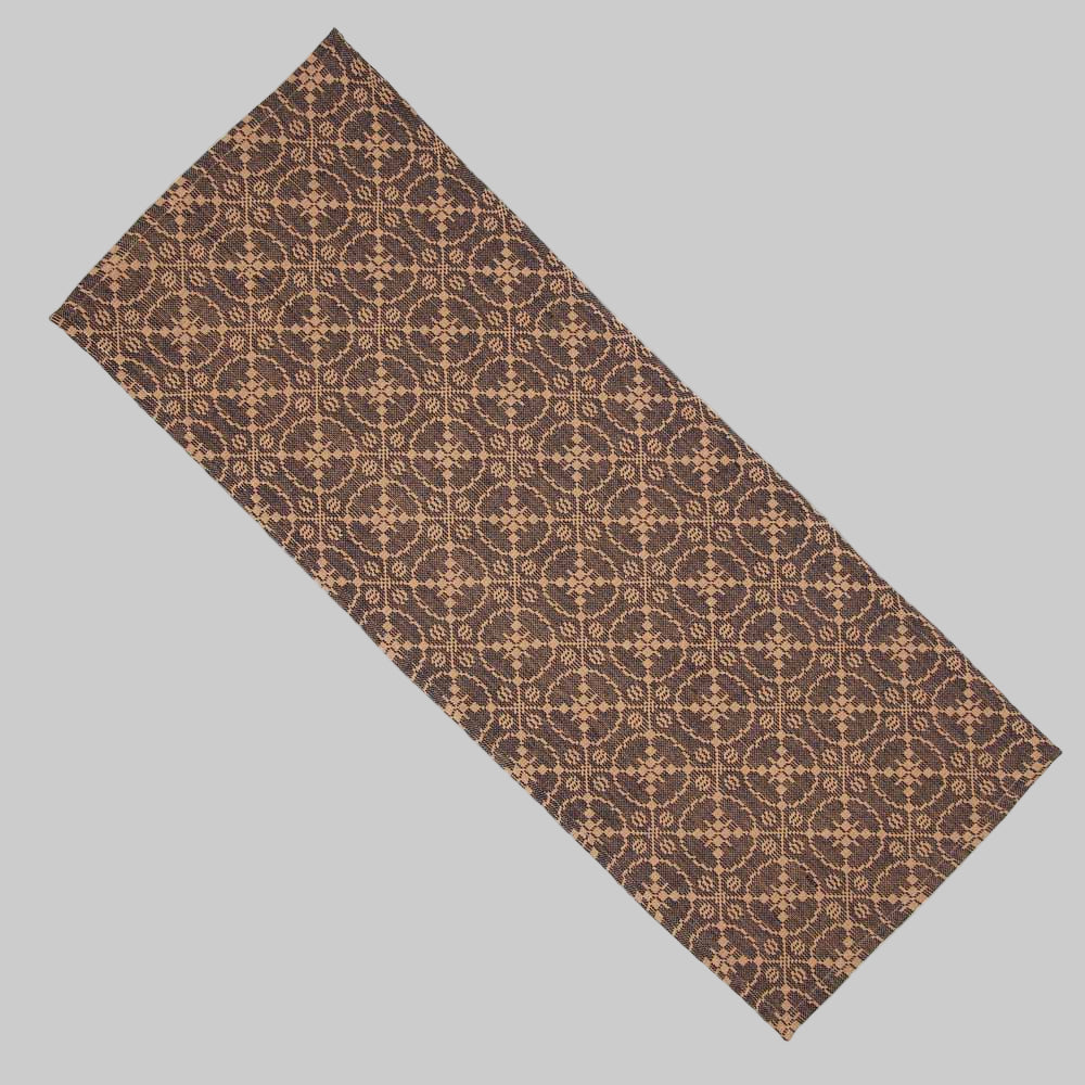 A jacquard table runner with a geometric pattern in black and tan colors.
