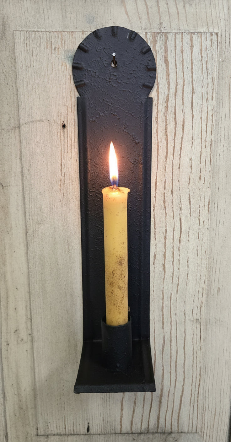A black metal candle sconce with a textured finish, designed to hold a taper candle, mounted on a wall.