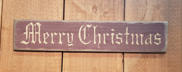 A wooden sign with the text 'Merry Christmas' written in a cursive script, placed against a wooden background.