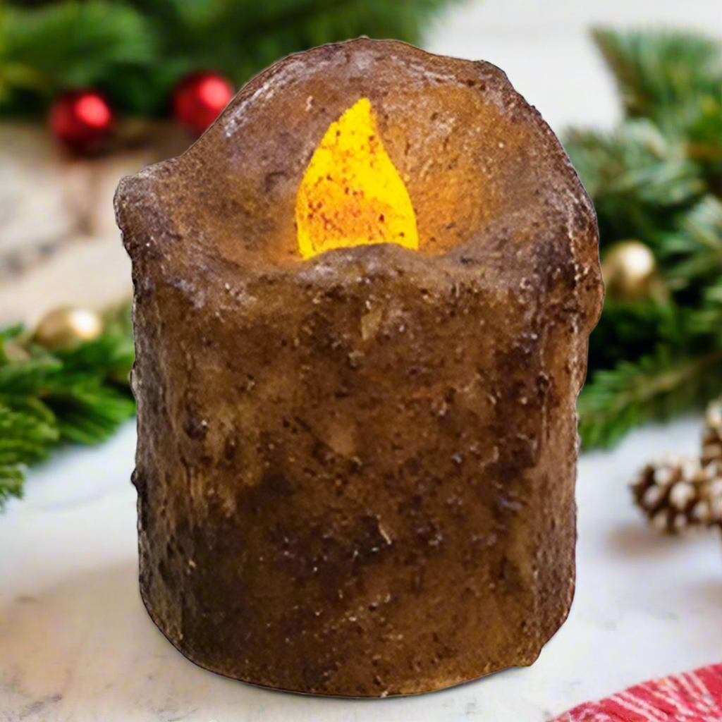 A brown wax mini drip timer pillar candle with an orange lit flame, coated in burnt mustard wax with a cinnamon scent.