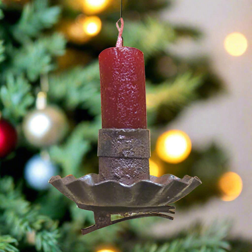A rusty metal fluted candle holder with an attached metal clip, designed to be attached to tree, wreath or garland branches.