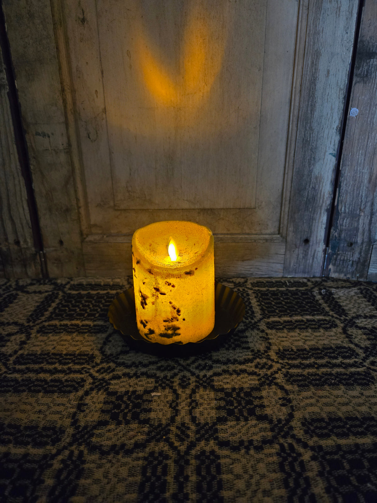 Battery operated pillar candle in a dimly lit room.