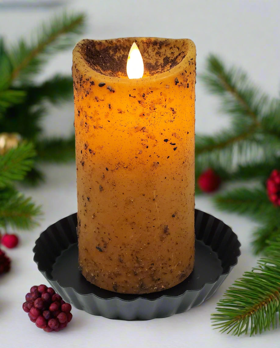 A moving flame pillar candle in a mustard yellow color, sitting on a black holder, with a visible flame at the top.