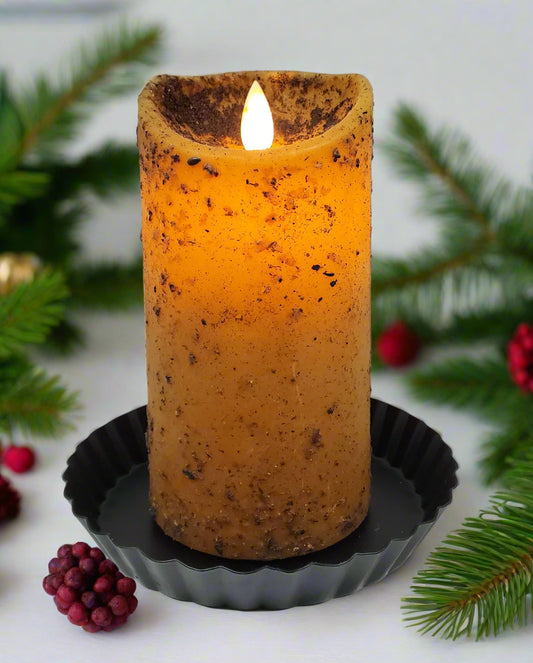 A moving flame pillar candle in a mustard yellow color, sitting on a black holder, with a visible flame at the top.
