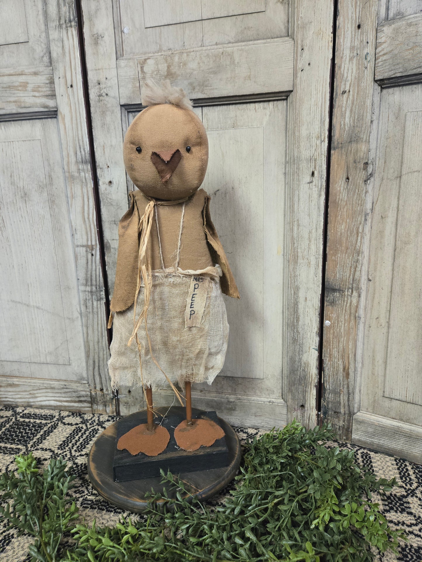 Primitive fabric stuffed chick on wood riser with greenery