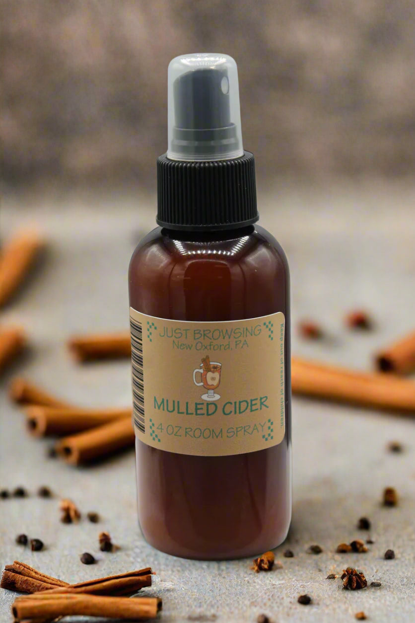 Brown spray bottle with a label on a gray background surrounded by cinnamon sticks and spices