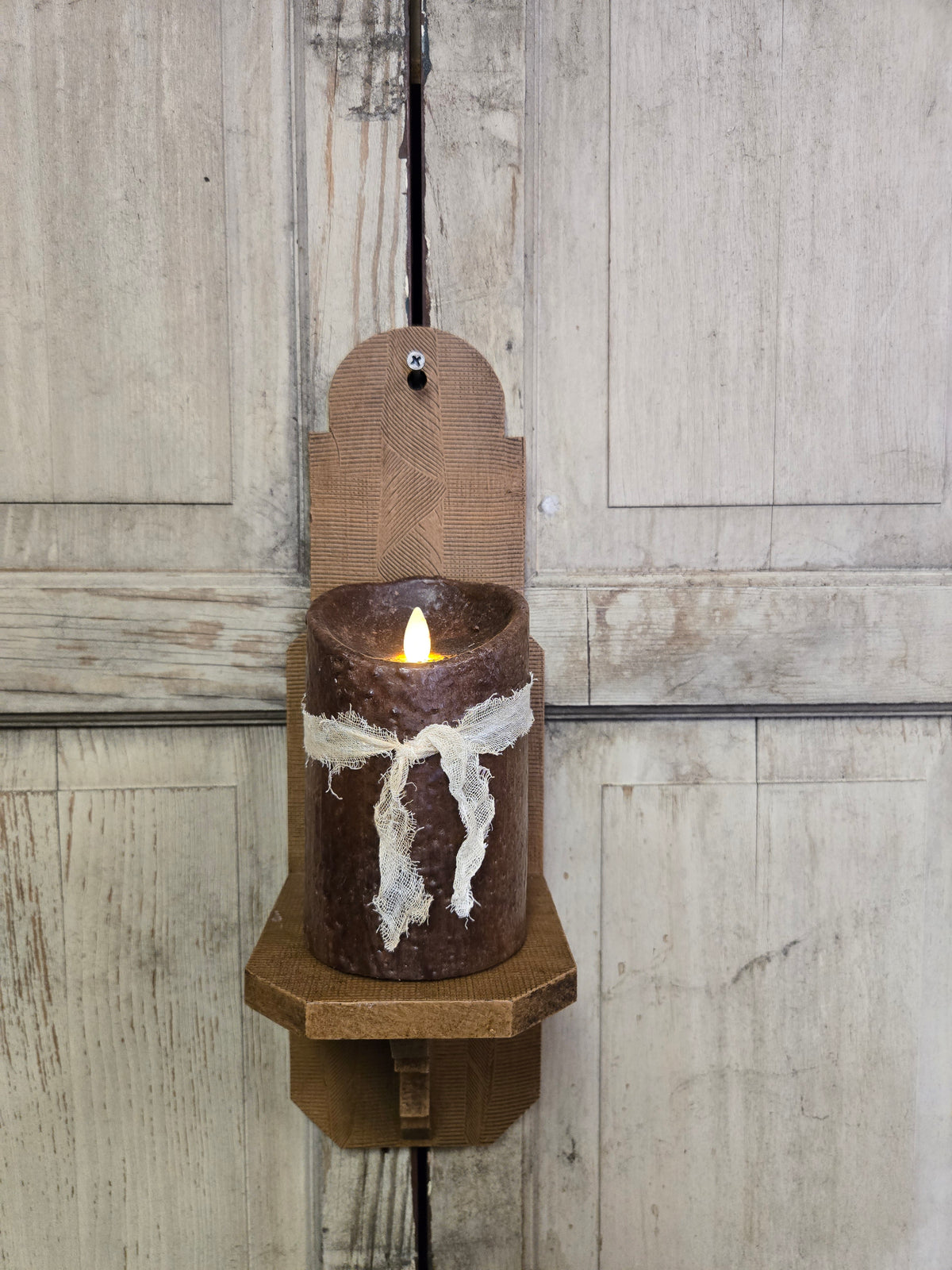 Wax candle in a wooden holder on a rustic wooden panel background