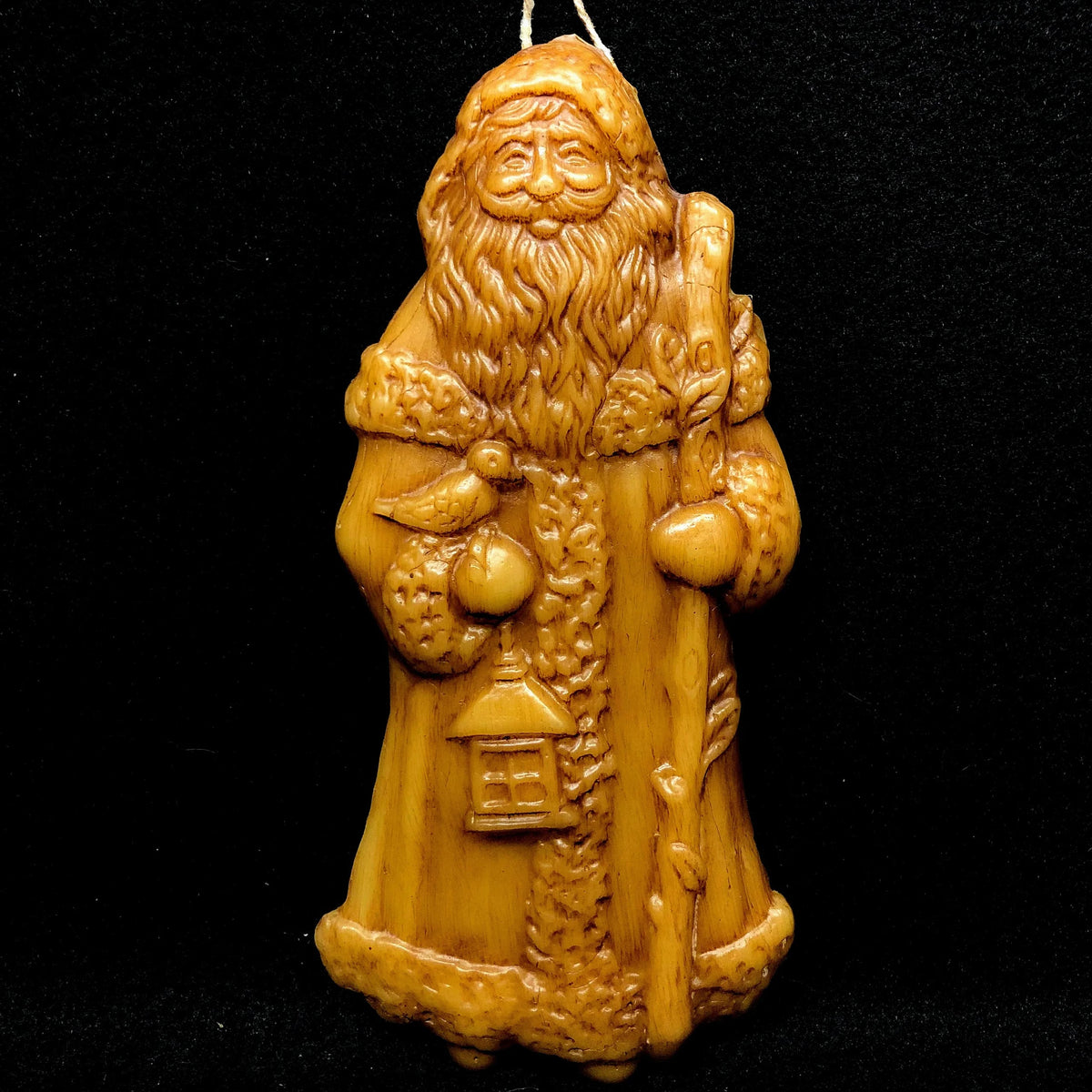 Beeswax Santa Claus ornament on a black background