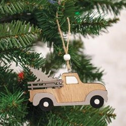 A wooden ornament in the shape of a vintage truck with a gray roof, hanging from a tree.