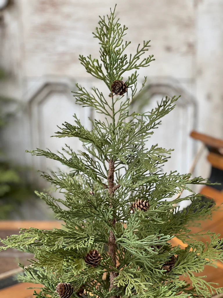 Realistic artificial Christmas tree with pinecones on a blurred indoor background