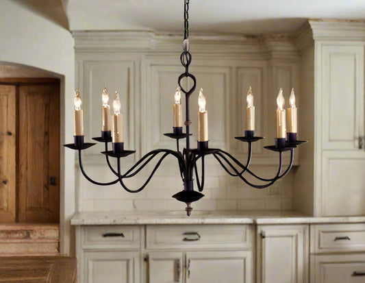 An Oakham wrought iron chandelier with eight lights, hanging from the ceiling. The chandelier appears to be black in color with a metallic finish.