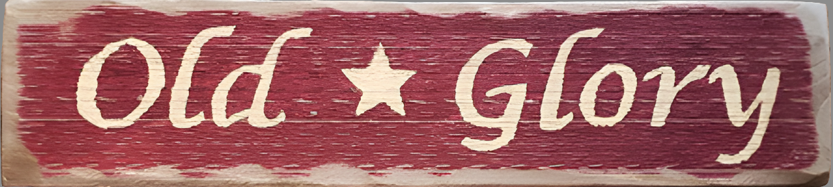 Weathered wood sign painted red with the words "Old Glory" and a star in the middle in cream