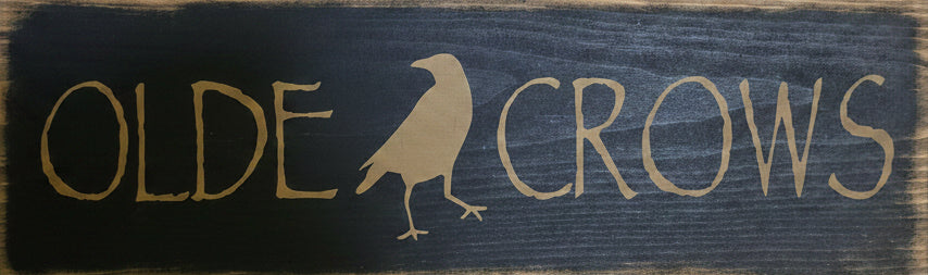 Wooden sign with 'Olde Crows' text and logo on a wooden background