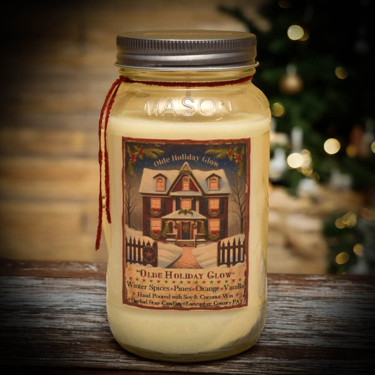 Mason jar candle with cream colored wax and artwork featuring a red home with fence and text