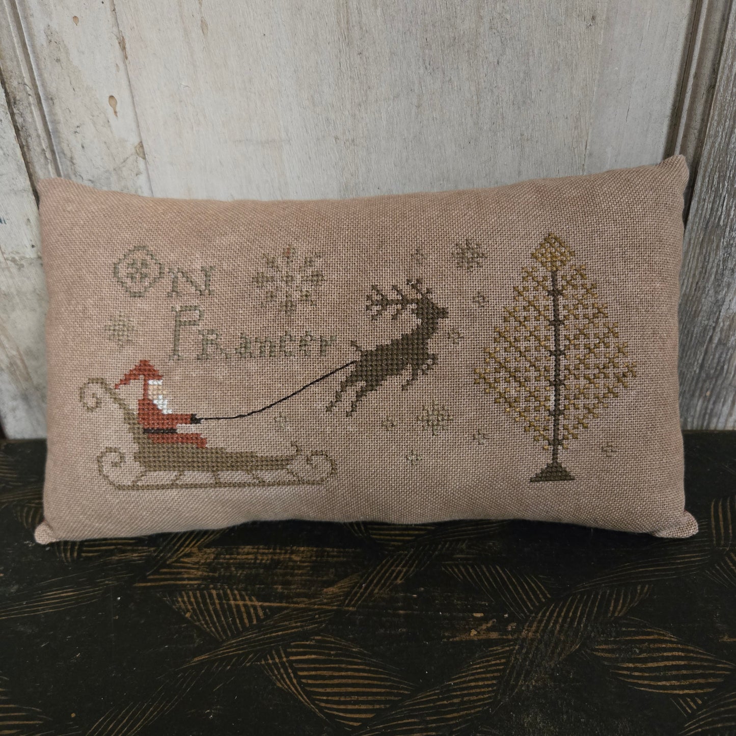 Decorative pillow with embroidered designs on a wooden surface