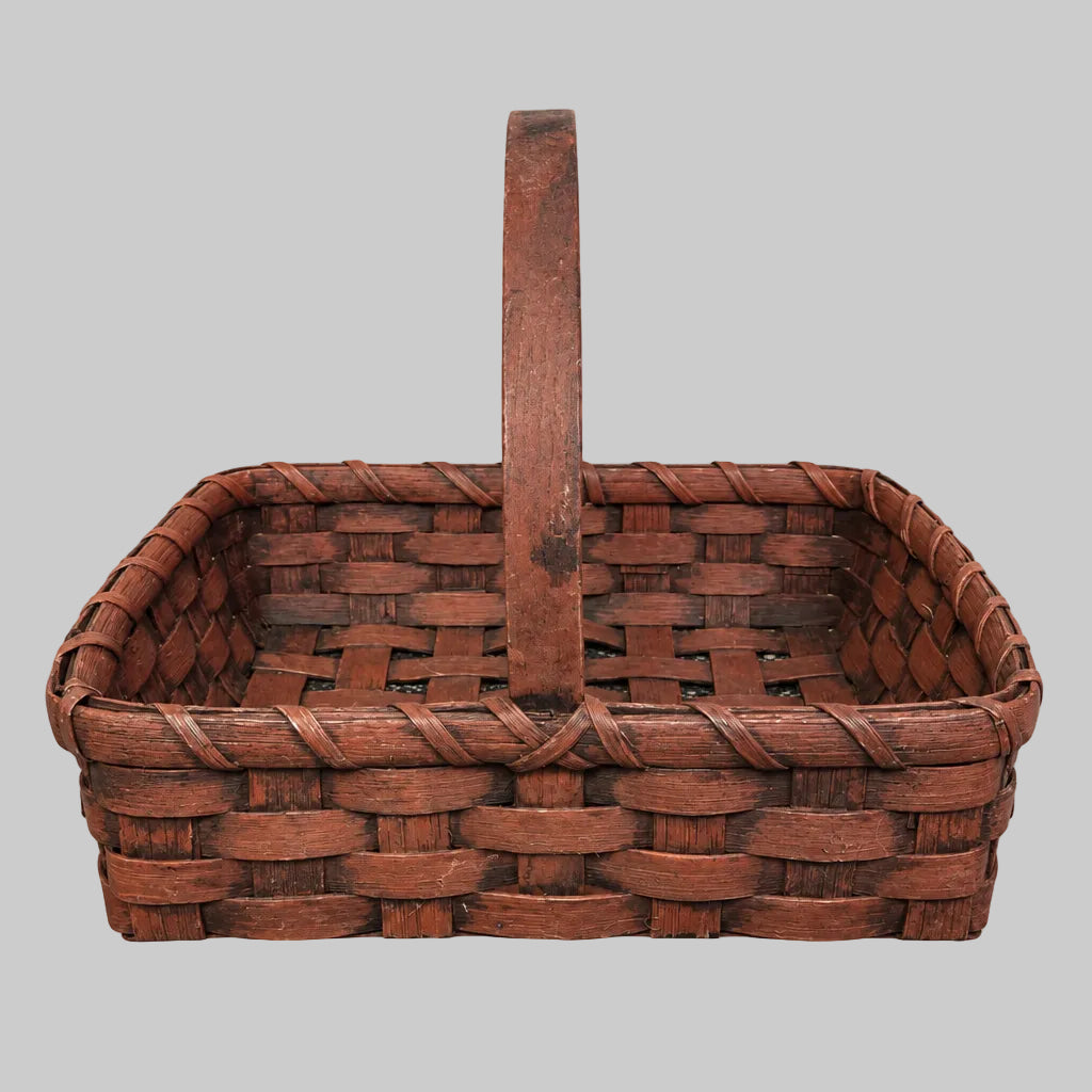 Burgundy hand woven basket on a grey background.