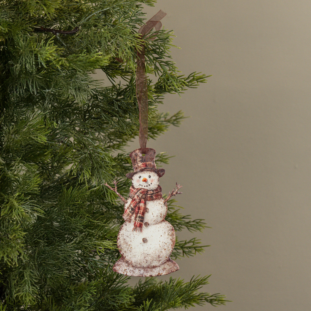 Snowman ornament hanging on a Christmas tree with a plain background