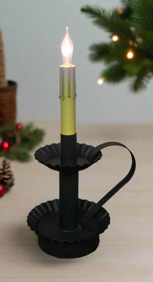 Decorative candle with a lit candle inside on a wooden surface with a Christmas tree in the background.