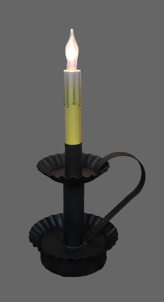 Decorative candle with a lit candle inside on a wooden surface with a Christmas tree in the background.