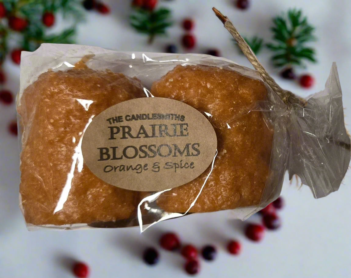 Two orange and spice scented candles packaged in a clear plastic bag with a label that reads 'The Candlesmiths Prairie Blossoms Orange & Spice'.