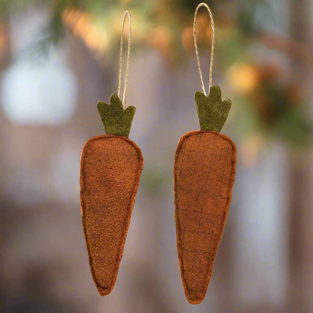 Two felt carrot ornaments with jute strings for hanging, one carrot is facing up and the other is facing down.