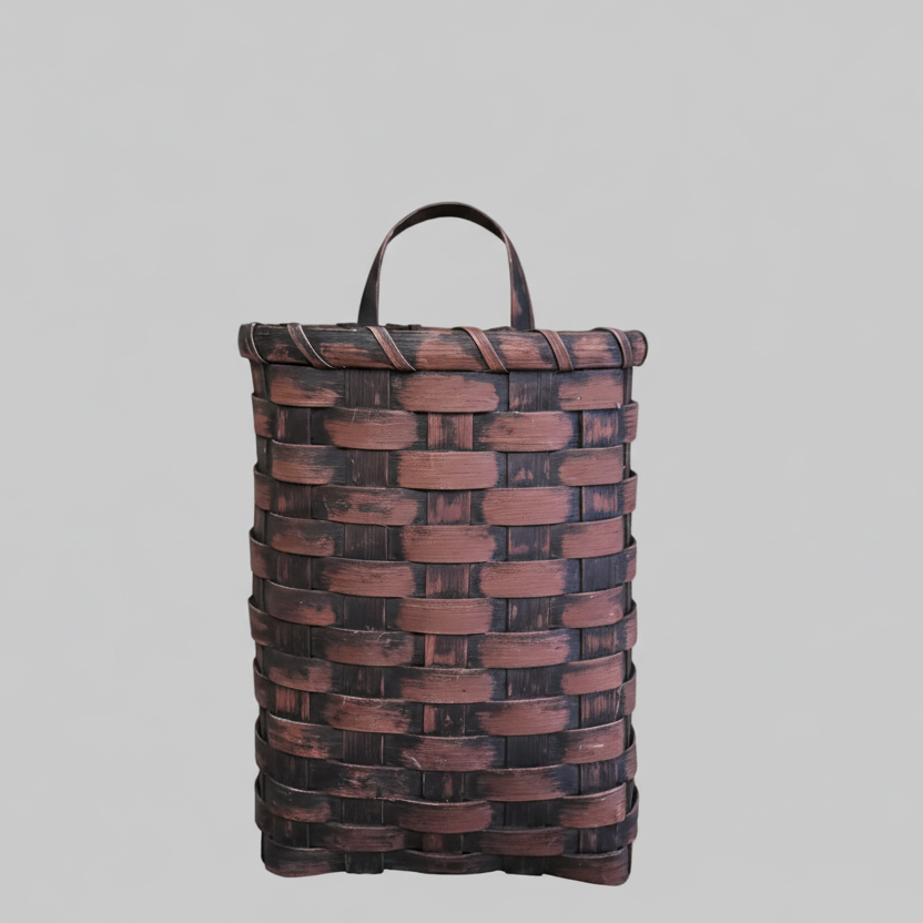 A handcrafted burgundy door basket with a geometric pattern design, hanging on a door.