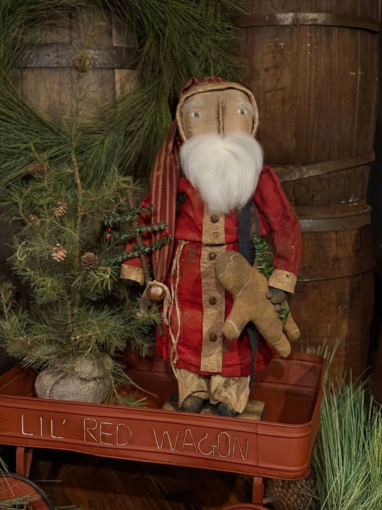 Vintage-style Santa Claus figure with a plaid coat in front of a wooden barrel and Christmas tree.