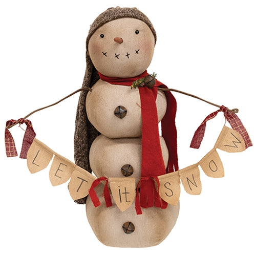 Primitive snowman doll with twig arms holding a ‘Let It Snow’ banner, wearing a red scarf and knit cap against a white background